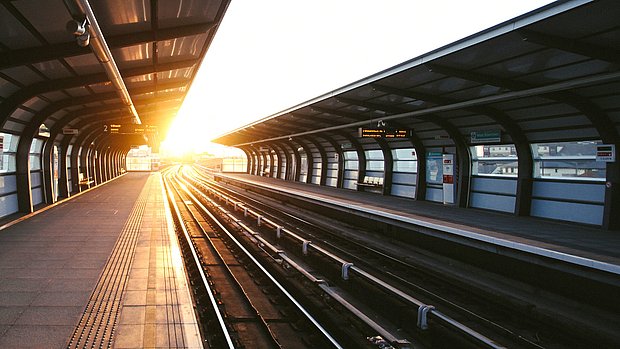 Sunlight shining through an empty train platform at a station, with tracks leading into the distance.