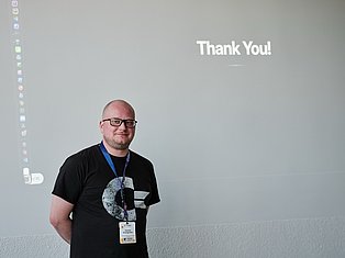 Man wearing glasses and ID badge smiling at camera with 'Thank You!' text displayed above