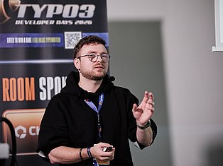 Developer speaking at TYPO3 Developer Days 2020 conference, wearing glasses and black hoodie with lanyard