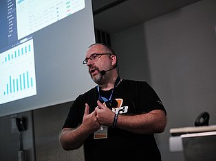 Man with headset presenting data analytics dashboard on projector screen during conference talk