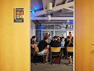 Group of people gathered in Pavillon 33 meeting room with yellow walls, sitting around table with laptops