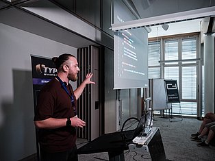Developer presenting code on projector screen at tech conference with audience