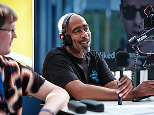 Man wearing headphones speaking into microphone during podcast or interview recording session