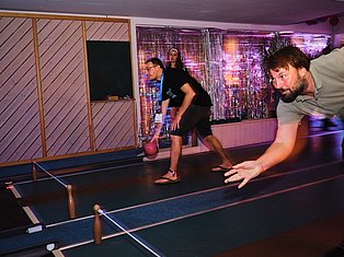 People playing bowling in an indoor alley with neon purple lighting and modern decor