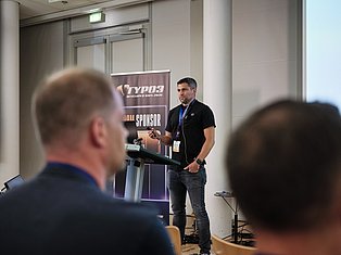 Speaker presenting at Typo3 Developer Days 2020 conference to audience members in indoor venue