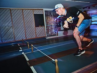 Man playing table tennis in indoor venue with blue lighting and decorative backdrop