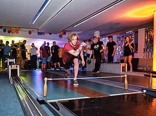 Person jumping rope at indoor party with colorful lighting and spectators watching in decorated venue