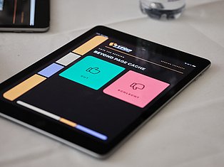 Tablet displaying colorful web design interface with turquoise and pink cards showing 'Beyond Page Cache' optimization features