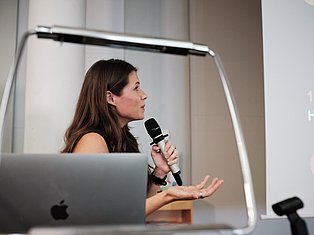 Woman speaking at podium with microphone and laptop during presentation