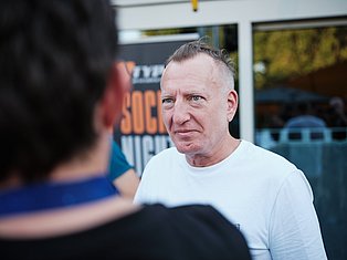 Man in white shirt having conversation with another person outdoors near storefront
