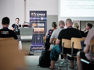 Speaker presenting at TYPO3 Developer Days 2020 conference podium to seated audience