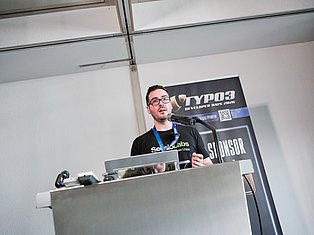 Man speaking at podium with microphone at DYP03 Developer Days 2020 conference