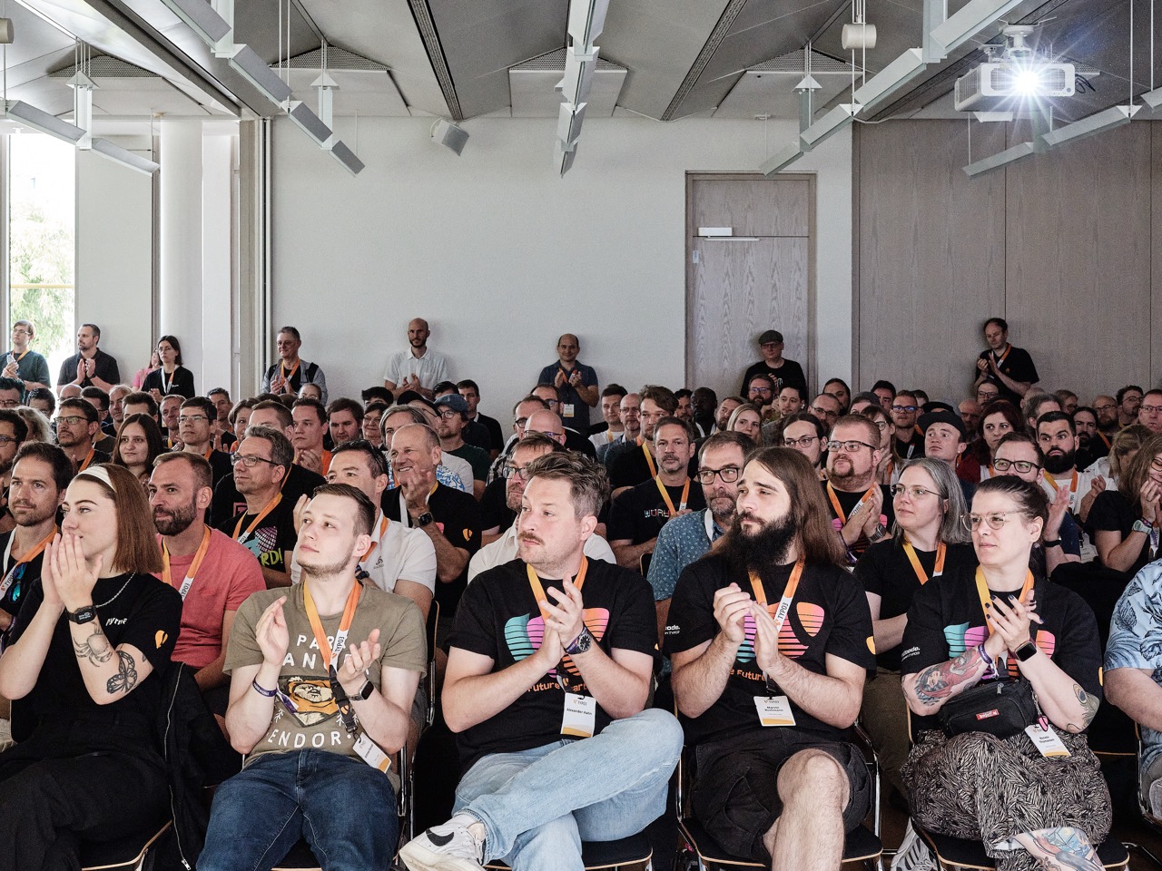 Audience seated in a bright room applauding at an event.